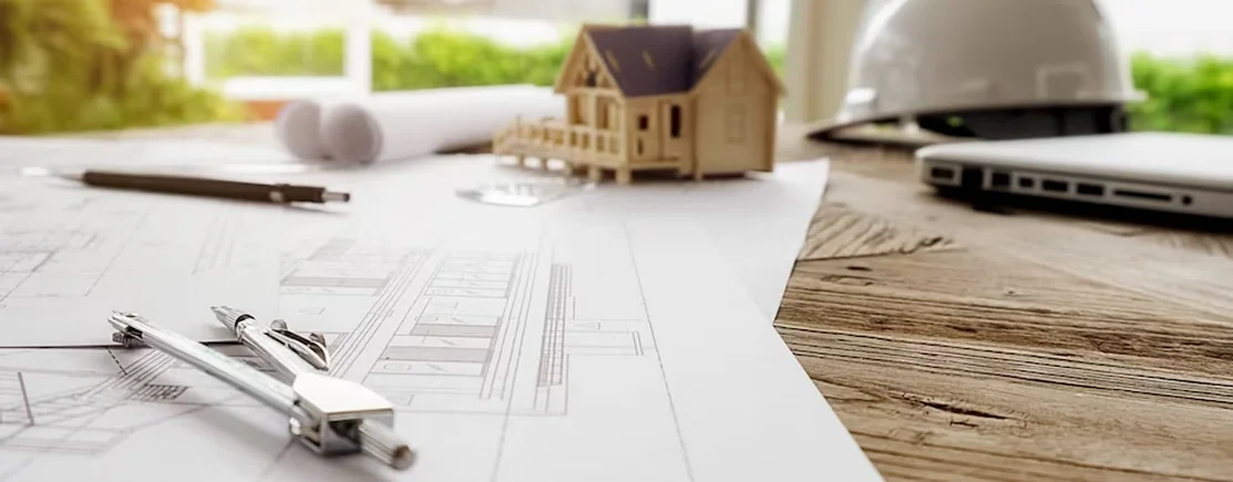 Изображение строительных чертежей с циркулем, каской, карандашом, макетом дома